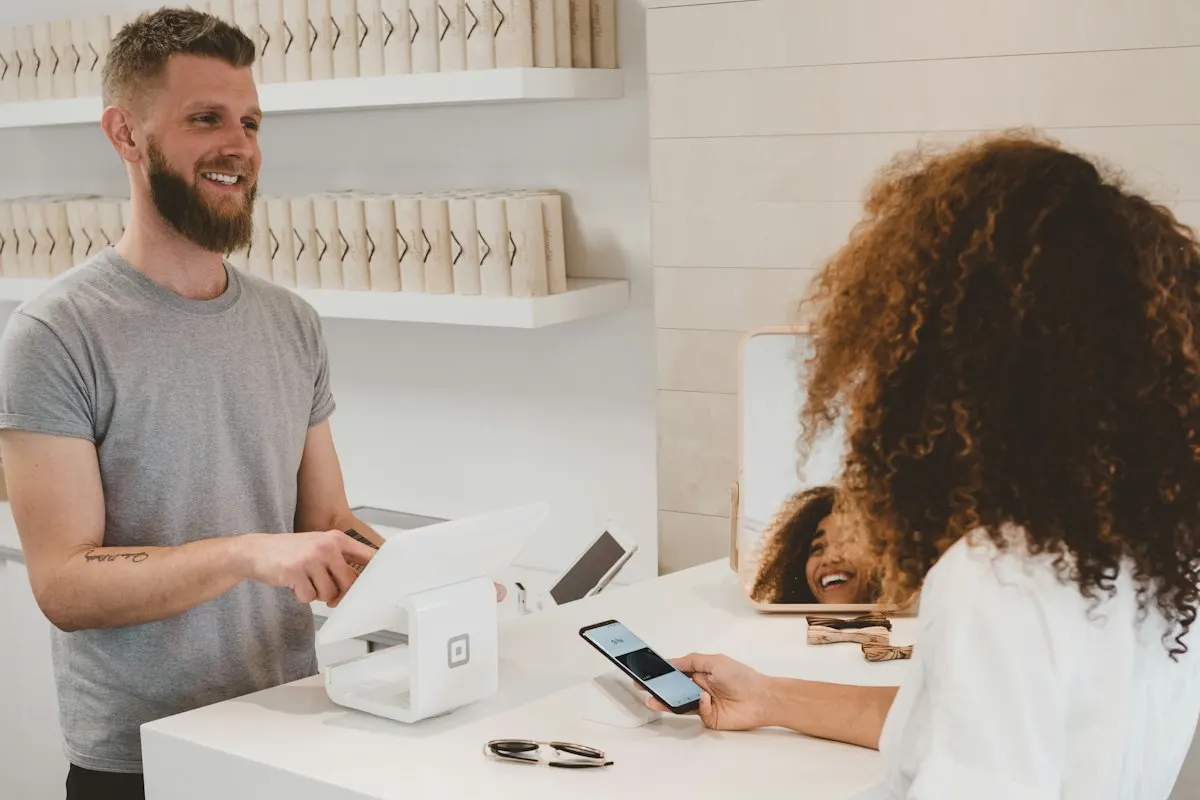 Collaborateur souriant accueillant une cliente au comptoir